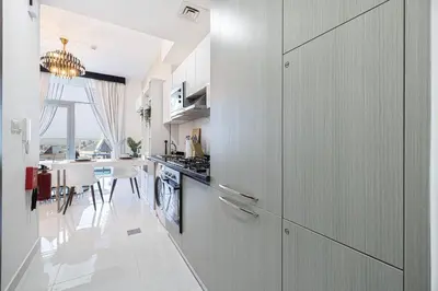 a kitchen with white cabinets and a dining room at Dubai Sleek & Cozy Space in Dubai