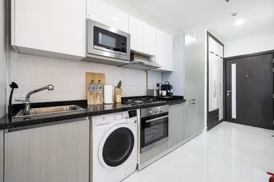 a kitchen with a sink and a washing machine at Dubai Sleek & Cozy Space in Dubai