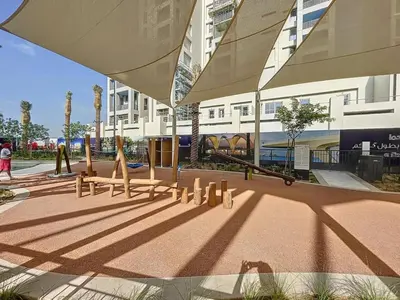 a park with benches and an umbrella in front of a building at Vida Residences at Creek Beach - Light Two Bedroom in Dubai