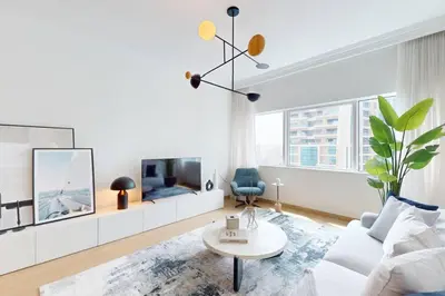a white living room with a couch and a tv at MAG 218 Tower - Elegant One Bedroom in Dubai