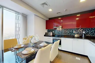 a kitchen with red cabinets and a table with chairs at Cayan Tower - Smart One Bedroom Loft on High Floor in Dubai