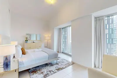 a white bedroom with a bed and a large window at Cayan Tower - Smart One Bedroom Loft on High Floor in Dubai