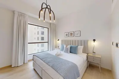 a white bedroom with a large bed and a window at Vacationer I Premium 1 Bed I Steps to JBR Beach & Nightlife I Bahar 6 Tower in Dubai