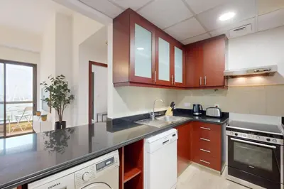 a kitchen with wooden cabinets and a counter top at Vacationer I Premium 1 Bed I Steps to JBR Beach & Nightlife I Bahar 6 Tower in Dubai