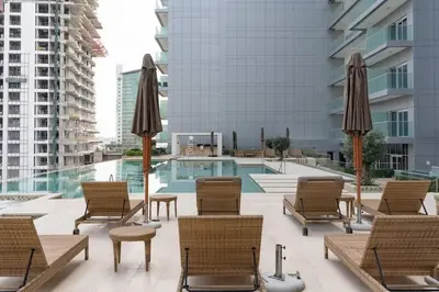 a patio with chairs and umbrellas next to a pool at Dazzling Studio Apartment in Business Bay l City View in Dubai