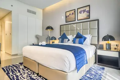 a bedroom with a large bed with blue and white pillows at Dazzling Studio Apartment in Business Bay l City View in Dubai