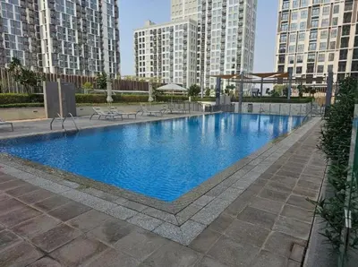 a large swimming pool in a city with tall buildings at 1BR Apartment in Park Heights 2 Dubai Hills in Dubai