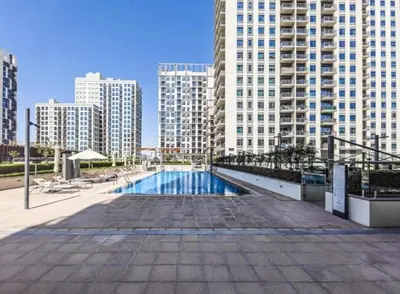 a swimming pool in a city with tall buildings at 1BR Apartment in Park Heights 2 Dubai Hills in Dubai