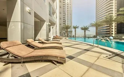 a hotel with a pool and lounge chairs next to a building at Spacious 1BR in the iconic Torch Tower, Dubai Marina - Allsopp&Allsopp in Dubai