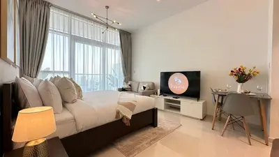 a bedroom with a large bed and a television at EasyGo - Carson Tower C Damac Hills Studio in Dubai