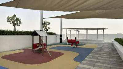 acovered area with chairs and a swing set on a building at EasyGo - Carson Tower C Damac Hills Studio in Dubai