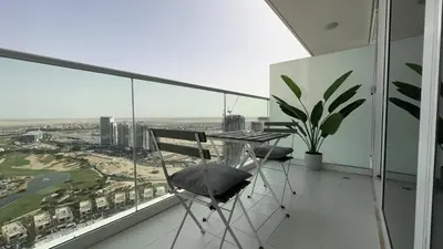 a balcony with a table and chairs and a view at EasyGo - Carson Tower C Damac Hills Studio in Dubai