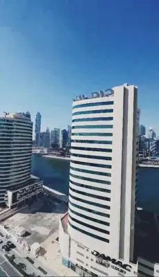 a tall white building in front of a city at Luxury Studio Apartment By DownTown in Dubai