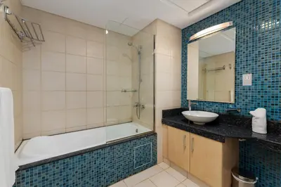 a bathroom with a tub and a sink and a mirror at Shoreline 7, Palm Jumeirah - Mint Stay in Dubai
