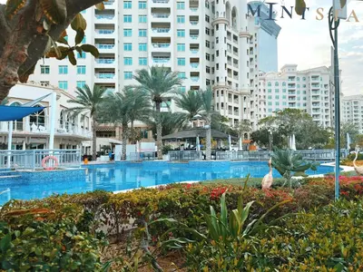 a large swimming pool with palm trees and buildings at Shoreline 7, Palm Jumeirah - Mint Stay in Dubai