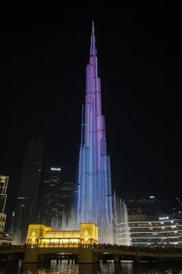 a tall building is lit up in blue and white at 4BR - Burj and Fountain View - Opposite Dubai Mall in Dubai