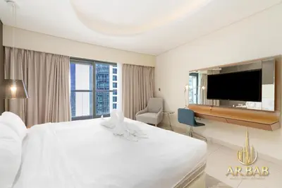 a bedroom with a white bed and a flat screen tv at Damac Paramount - Luxurious 2BR - Stunning Dubai Canal View - High Level in Dubai