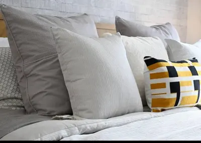 a bed with gray and white pillows on it at Dubai Hills Collective Tower 2 in Dubai