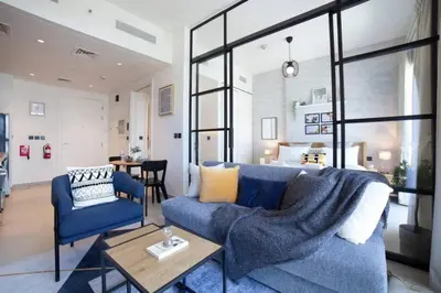 a living room with a blue couch and a table at Dubai Hills Collective Tower 2 in Dubai