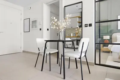a dining room with a black table and white chairs at Silkhaus Chic 1BDR in Exclusive Neighbourhood in Dubai