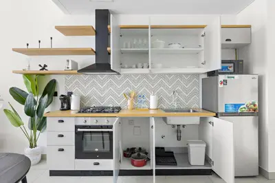 a kitchen with white cabinets and a stove and refrigerator at Silkhaus Chic 1BDR in Exclusive Neighbourhood in Dubai