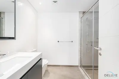a white bathroom with a shower and a sink at Lovely 2BR at Belgravia Square, JVC by Deluxe Holiday Homes in Dubai