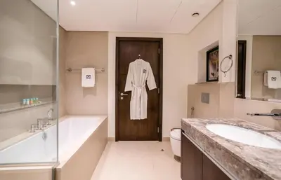 a bathroom with a sink and a robe hanging on the door at Superior New Luxury Living 2BR Apt Dubai Creek Harbour in Dubai