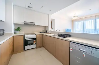 a kitchen with white cabinets and a stove top oven at Homes Beyond l Spacious 2BR Creekside Lifestyle in Dubai