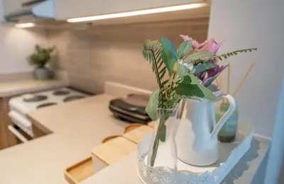 a vase with flowers in it on a kitchen counter at Homes Beyond l Spacious 2BR Creekside Lifestyle in Dubai