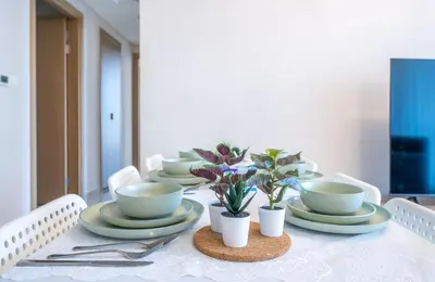 a table with plates and cups and potted plants on it at Homes Beyond l Spacious 2BR Creekside Lifestyle in Dubai