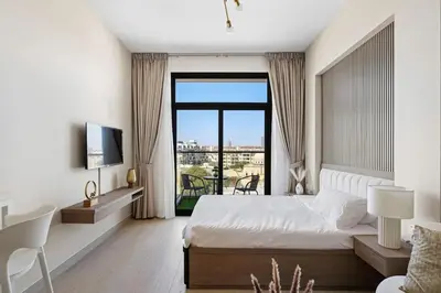 a bedroom with a bed and a large window at Modern Studio in residence with pool gym and paddl in Dubai
