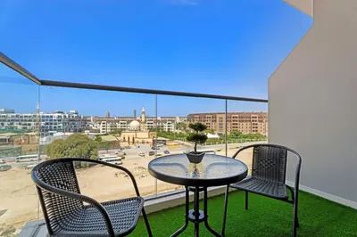 a table and chairs on a balcony with a view of a city at Modern Studio in residence with pool gym and paddl in Dubai