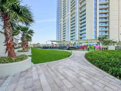 a walkway in a park with palm trees and buildings at High-Floor 2BR in Aykon City Spacious, Good View in Dubai