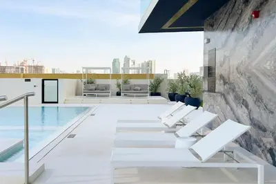a pool with white chairs and a swimming pool at GuestReady - Marvellous home at Binghatti Heights in Dubai