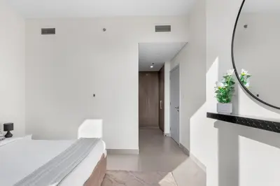 a bedroom with white walls and a bed and a mirror at Luxury 4-Bed Escape in Downtown Dubai That Sleeps 9 in Dubai