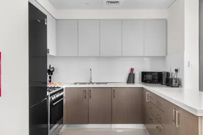 a kitchen with white cabinets and a black refrigerator at Luxury 4-Bed Escape in Downtown Dubai That Sleeps 9 in Dubai
