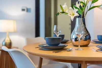 a wooden table with a vase of flowers and a cup at DIFC 1BR at SkyGardens Tower in Dubai