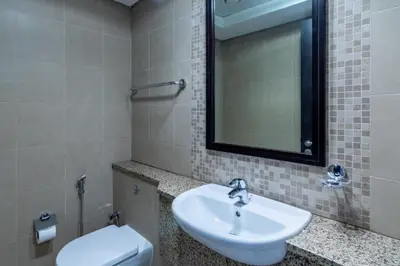 a bathroom with a sink and a toilet and a mirror at DIFC 1BR at SkyGardens Tower in Dubai