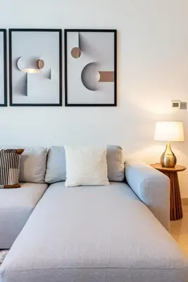 a living room with a couch and three pictures on the wall at DIFC 1BR at SkyGardens Tower in Dubai
