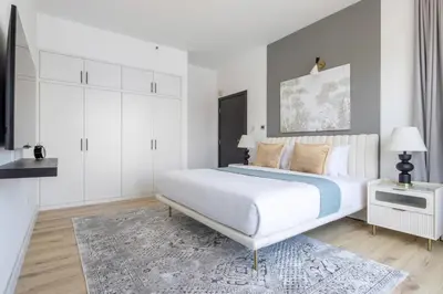 a white bedroom with a large bed and a rug at Frank Porter - La Riviera Tower in Dubai