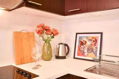 a kitchen counter with a vase of flowers and a picture at Heart of DIFC: SKY Gardens Modern Chic Studio in Dubai