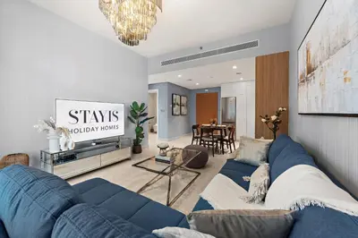 a living room with a blue couch and a table at Stayis I Beachfront Luxury 1BR with Private Access in Dubai