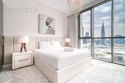 a white bedroom with a bed and a large window at Downtown Views I - Burj Khalifa View, Downtown Dubai in Dubai