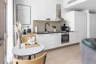 a kitchen with white cabinets and a white table at Silkhaus Modern Studio in The Heart of DIFC in Dubai