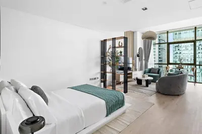 a white bedroom with a large bed and a living room at Silkhaus Modern Studio in The Heart of DIFC in Dubai