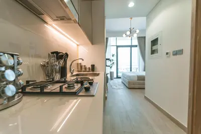 a kitchen with a stove top oven next to a living room at Wonderful Studio with Balcony & City Views in Dubai