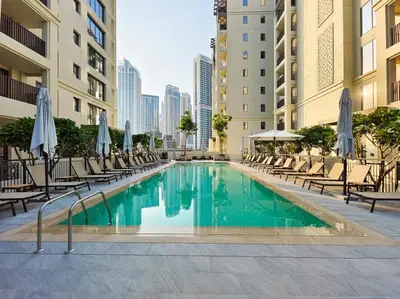 a swimming pool in a building with chairs and umbrellas at Sunset Creek Oasis: 1BR Gem Luxury Beach Apartment in Dubai