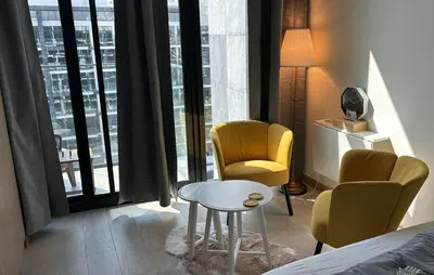 a bedroom with two chairs and a table in front of a window at Stylish Studio Retreat in Dubai