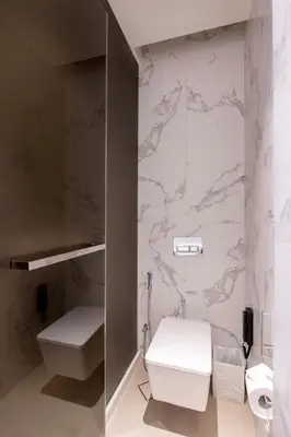 a bathroom with a toilet and a wall with marble at Address Opera Residences Burj Khalifa View in Dubai