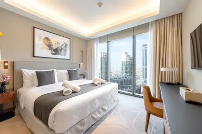 a bedroom with a large bed with a desk and a large window at Address Opera Residences Burj Khalifa View in Dubai